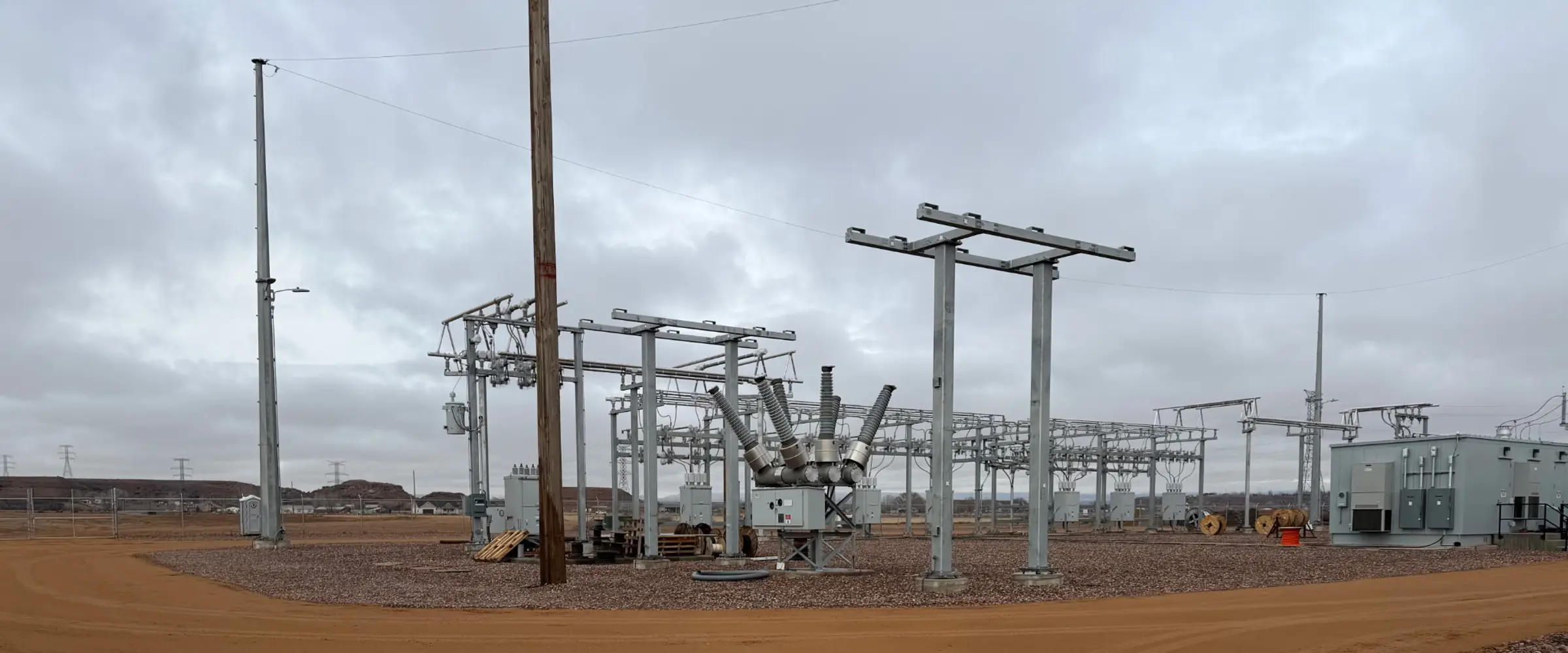 Completed substation yard with steel structures, a circuit breaker, and a control building