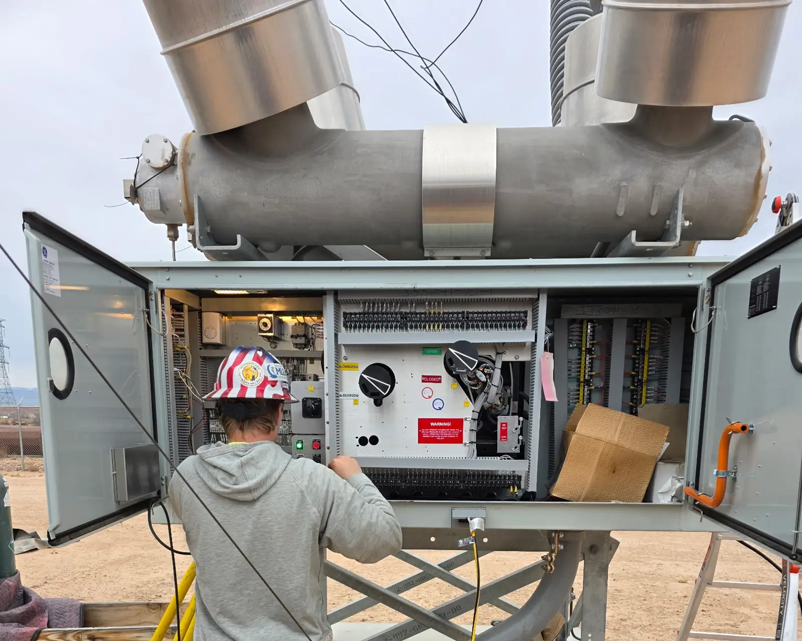 Technician working in the open control cabinet of an SF6 power circuit breaker