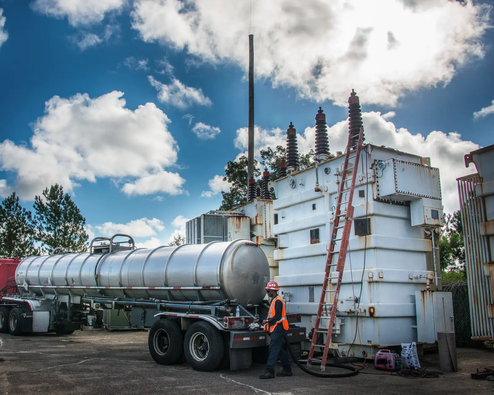 Field crew beside a large power transformer and an insulating-oil tanker truck