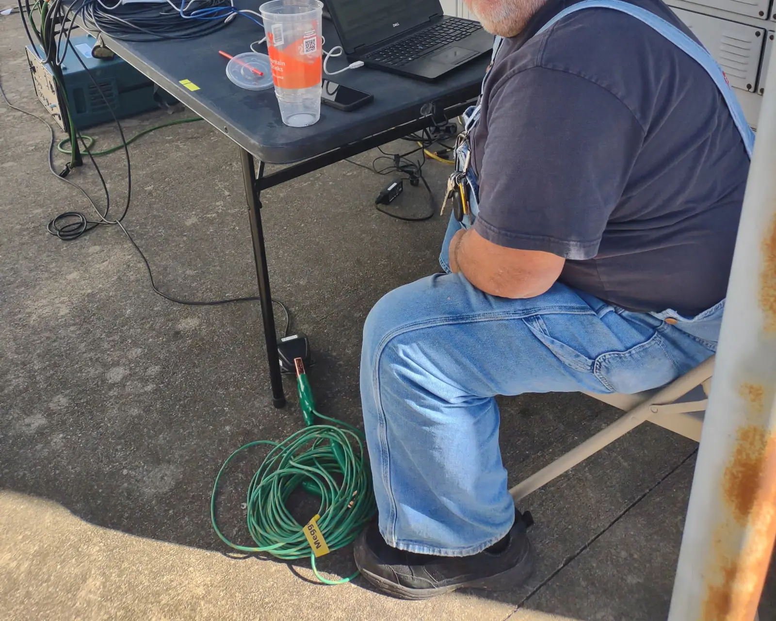 Technician at a laptop and test set beside high-voltage switchgear